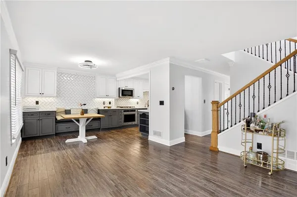 a living room with furniture a wooden floor and a view of kitchen