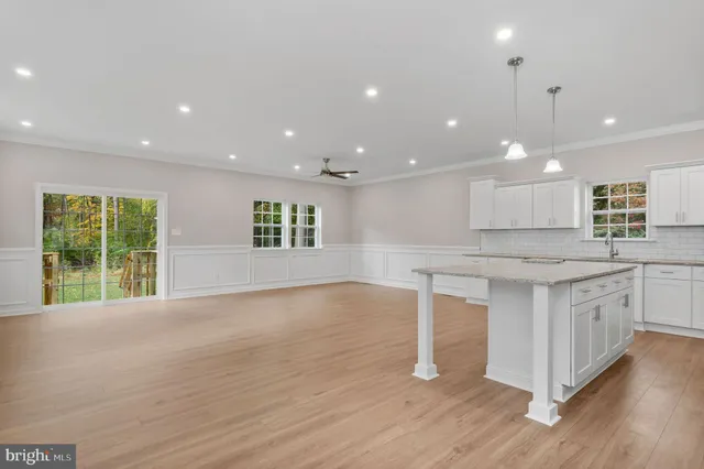 a view of large kitchen with granite countertop kitchen island wooden floors and white cabinets