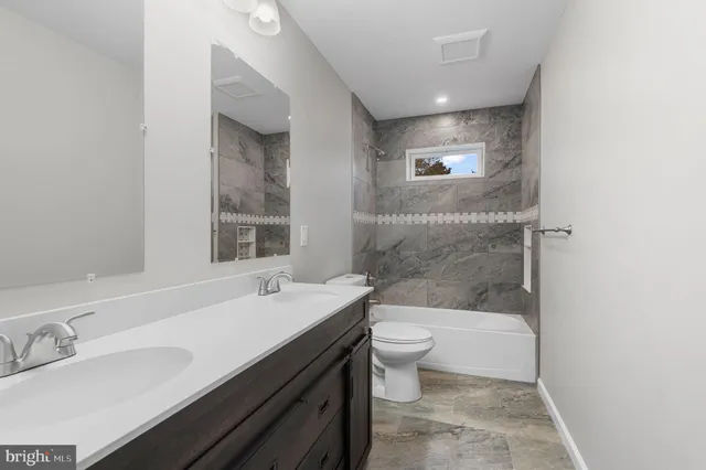 a bathroom with a bathtub shower sink mirror and toilet