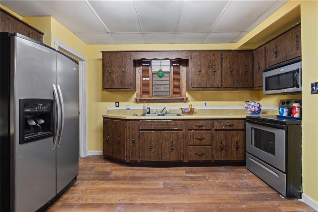 999 Thompson Avenue Donora, PA 15033 - Photo 11 of 24 a kitchen with stainless steel appliances granite countertop a refrigerator a stove and a sink with wooden cabinets