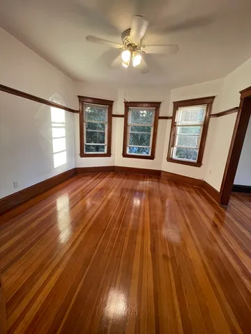 a view of an empty room with wooden floor and a window