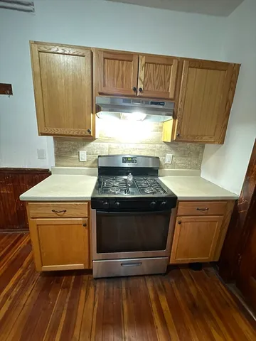 a kitchen with granite countertop a stove a sink and a refrigerator