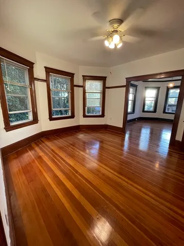 a view of an empty room with window and wooden floor