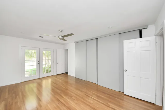 an empty room with wooden floor cabinet and windows