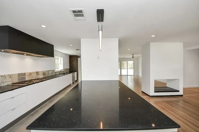 a view of a kitchen with kitchen island a sink stainless steel appliances and a counter top space