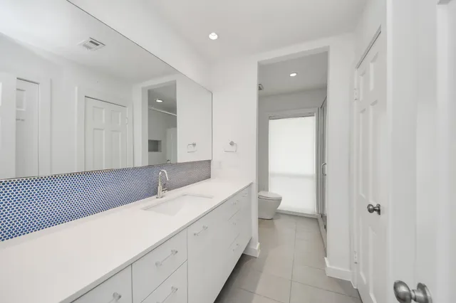a bathroom with a granite countertop sink a mirror and shower