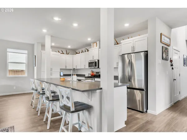 a kitchen with stainless steel appliances granite countertop a refrigerator a sink and white cabinets