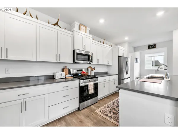 a open kitchen with stainless steel appliances granite countertop a refrigerator a stove a dining table and chairs with wooden floor