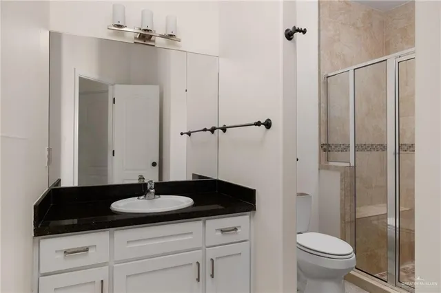 a bathroom with a granite countertop sink toilet a mirror and shower