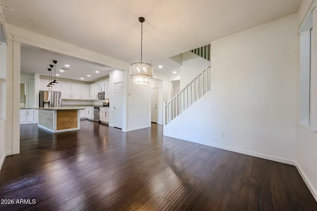 a view of a room with wooden floor kitchen appliances and a chandelier