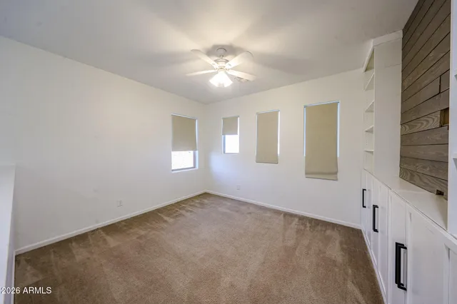 a view of an empty room with window and chandelier fan