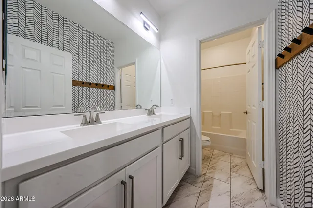 a bathroom with a double vanity sink a mirror and a bathtub
