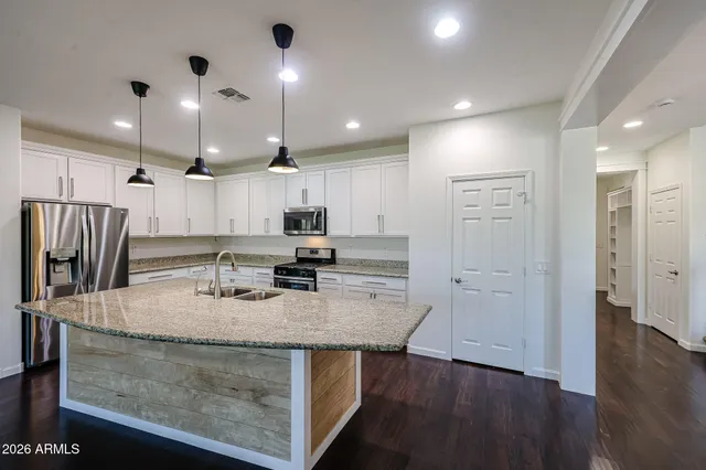 a kitchen with stainless steel appliances granite countertop a sink refrigerator and cabinets