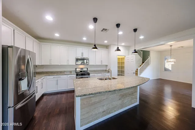 a kitchen with a refrigerator a sink and wooden floor