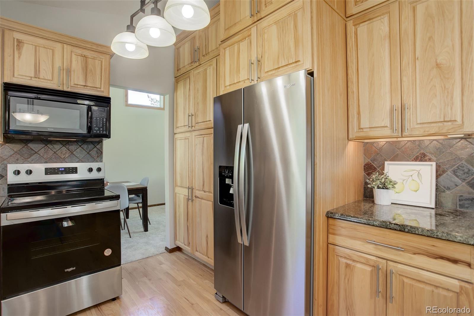 7877 West 110th Drive Westminster, CO 80021 - Photo 12 of 46 a kitchen with granite countertop a refrigerator stove and microwave