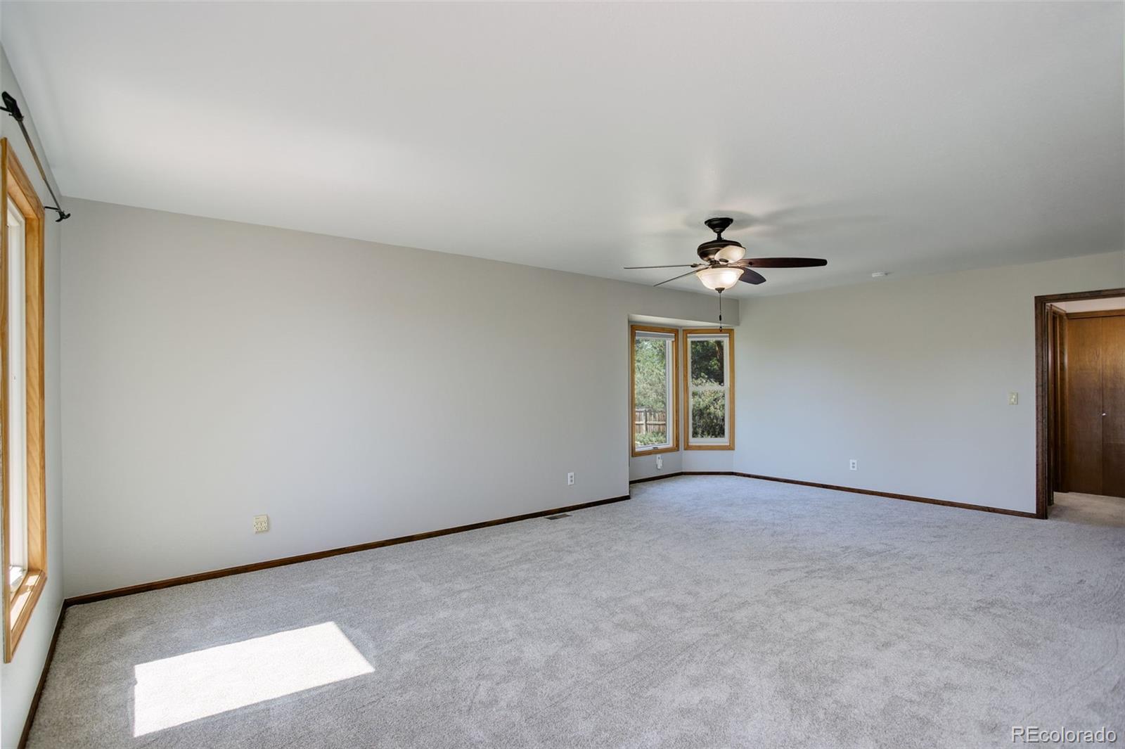 7877 West 110th Drive Westminster, CO 80021 - Photo 21 of 46 an empty room with chandelier fan and windows