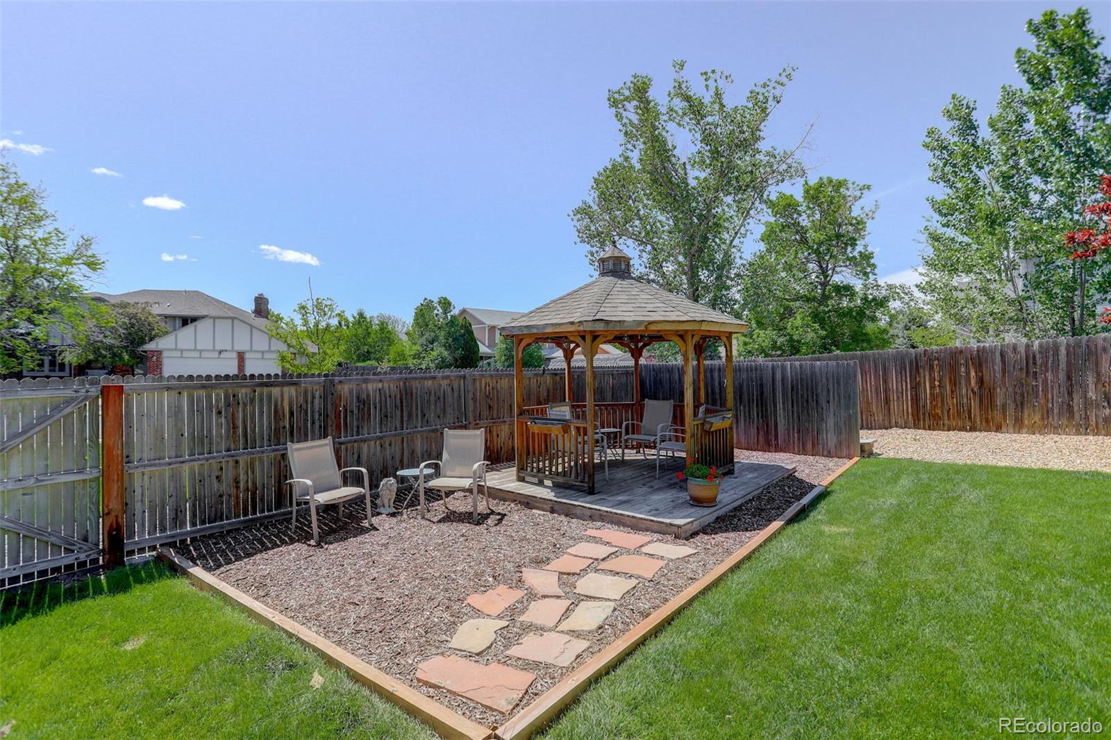 7877 West 110th Drive Westminster, CO 80021 - Photo 38 of 46 a view of a backyard with table and chairs under an umbrella with wooden fence
