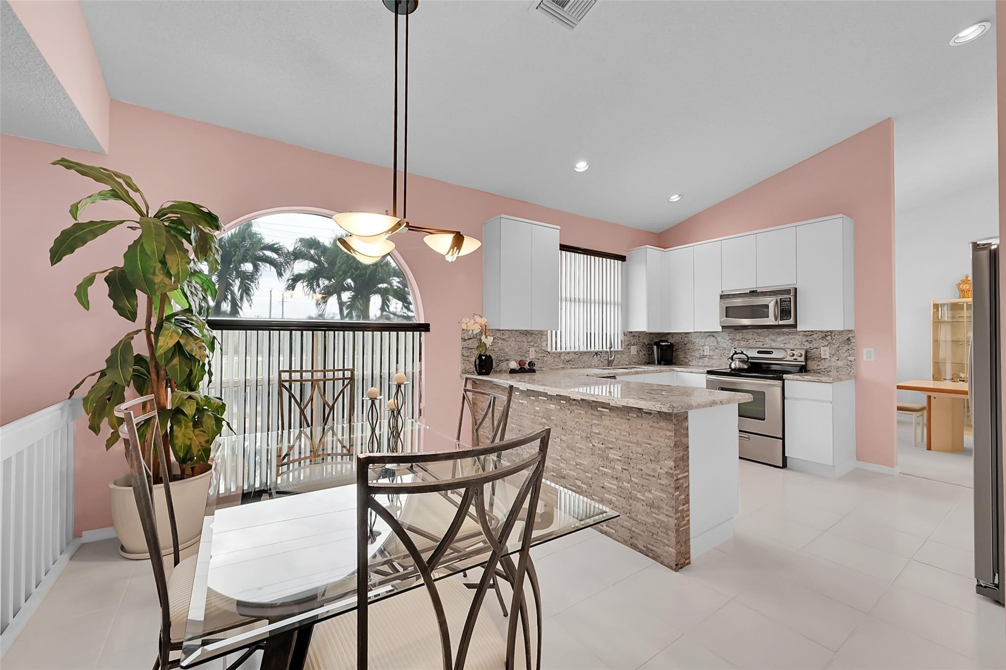 19640 Dinner Key Drive Boca Raton, FL 33498 - Photo 8 of 44 a kitchen with stainless steel appliances granite countertop a stove top oven a sink a dining table and chairs with wooden floor