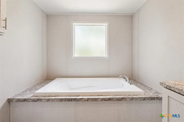 a bathroom with a granite countertop sink and tub