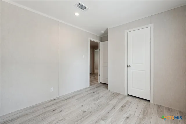a view of an empty room with wooden floor and closet