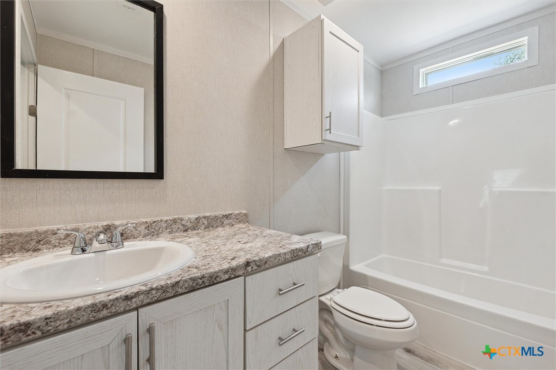 855 Roosevelt Road Luling, TX 78648 - Photo 27 of 47 a bathroom with a granite countertop sink a toilet and bathtub