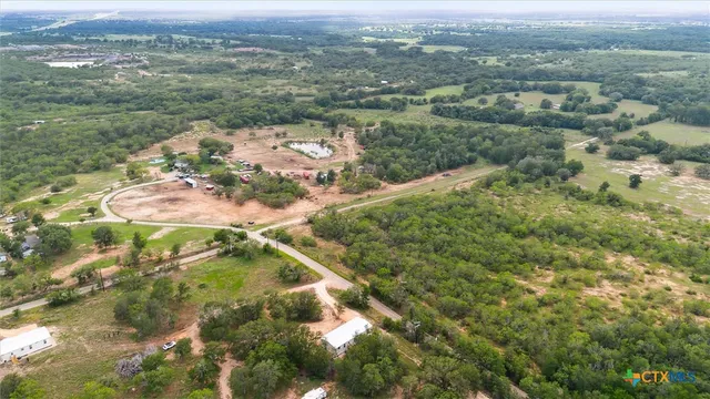an aerial view of residential houses with outdoor space and trees