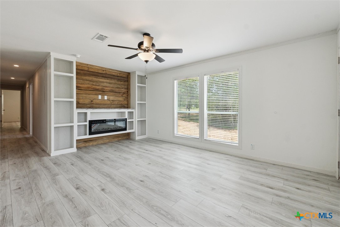 855 Roosevelt Road Luling, TX 78648 - Photo 8 of 47 an empty room with wooden floor ceiling fan and windows