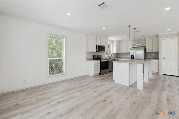 a kitchen with stainless steel appliances granite countertop a refrigerator a stove a sink and a granite counter tops with white cabinets