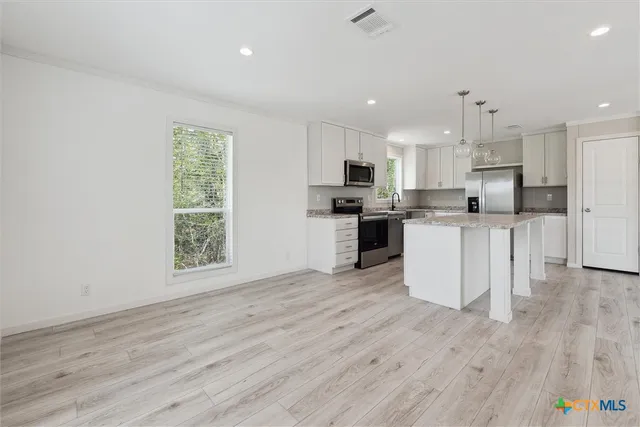 a kitchen with stainless steel appliances a microwave a stove a sink dishwasher and a refrigerator with wooden floor