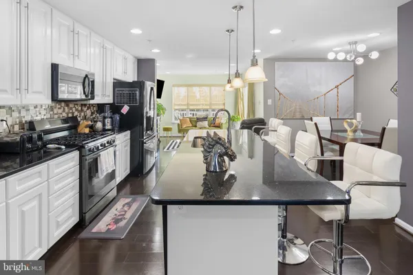 a kitchen with kitchen island granite countertop a table chairs sink and cabinets