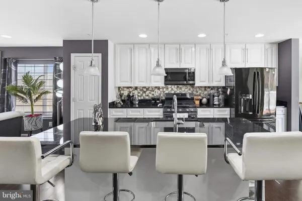 a kitchen with stainless steel appliances a refrigerator a stove a sink a dining table and chairs