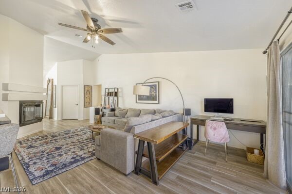1536 Pony Ranch Circle Henderson, NV 89014 - Photo 7 of 23 Living room featuring light wood finished floors, a fireplace, a ceiling fan, an office area, and high vaulted ceiling
