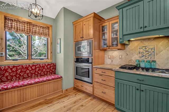 255 Summit Road Manitou Springs, CO 80829 - Photo 16 of 48 Open concept kitchen with leathered granite countertops, pullout pantry shelves, custom knotty hickory cabinetry, window seat with storage, knotty pecan flooring, breakfast bar seating and custom painted aspen tiles!
