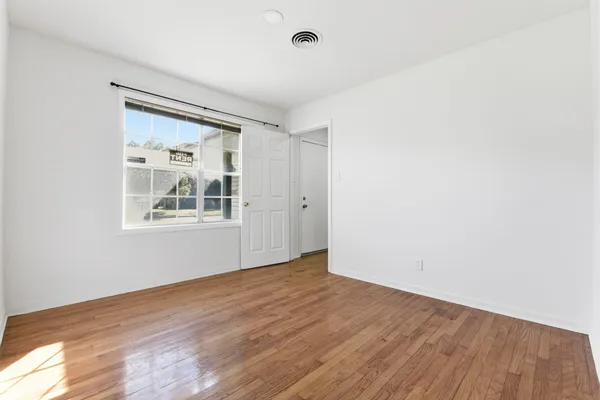 a view of empty room with wooden floor and fan