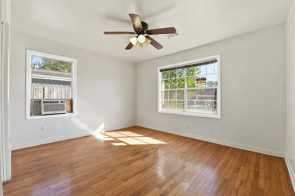 a view of an empty room with wooden floor and a window