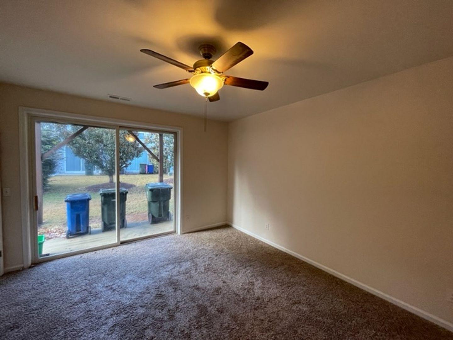 1672 Brook Fern Way Raleigh, NC 27609 - Photo 4 of 14 a view of an empty room with a fireplace and a ceiling fan
