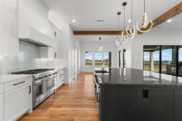 a kitchen with granite countertop a stove a sink a dining table and chairs with wooden floor