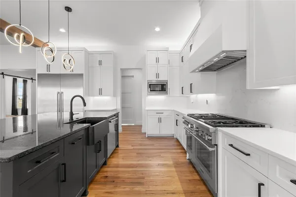 a kitchen with stainless steel appliances granite countertop a sink a stove and a wooden floors