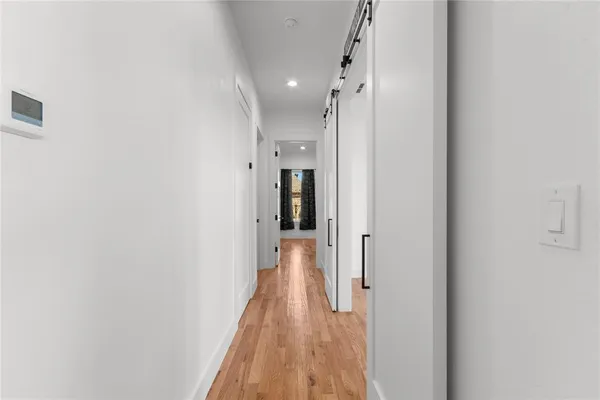 a view of a hallway with wooden floor and a bathroom