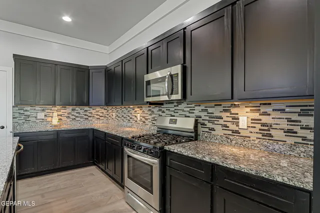 a kitchen with stainless steel appliances granite countertop a sink stove and refrigerator