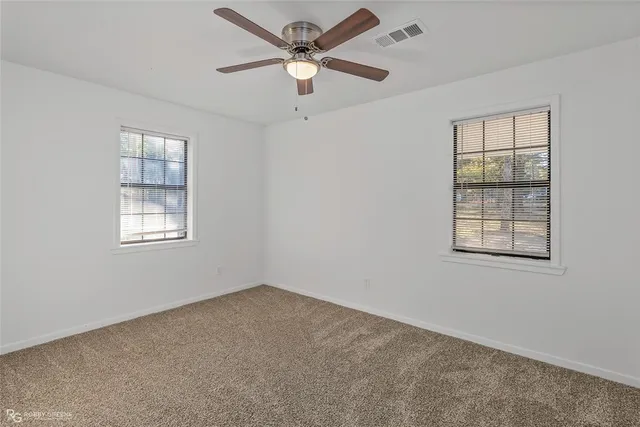 an empty room with a window and a fan