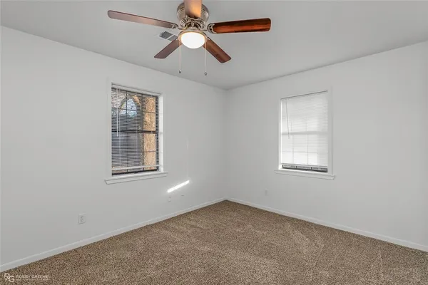 an empty room with windows and fan