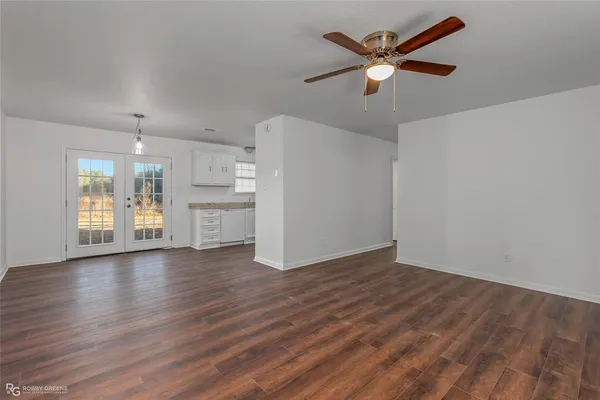 a view of an empty room with window and wooden floor