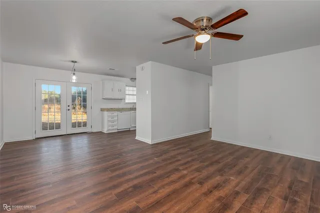 a view of an empty room with window and wooden floor