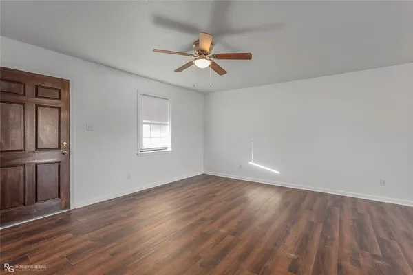 an empty room with wooden floor chandelier fan and windows