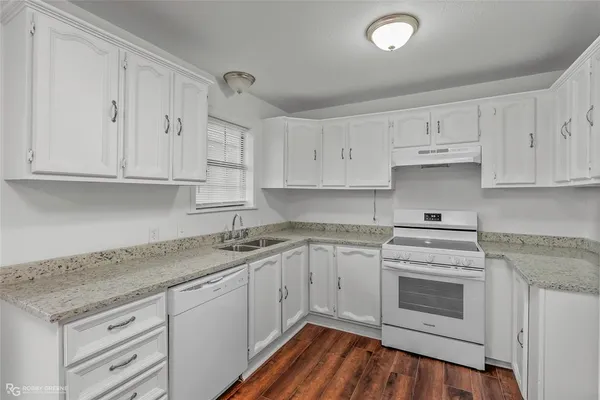 a kitchen with granite countertop white cabinets and white appliances