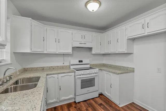 a kitchen with granite countertop white cabinets and white appliances