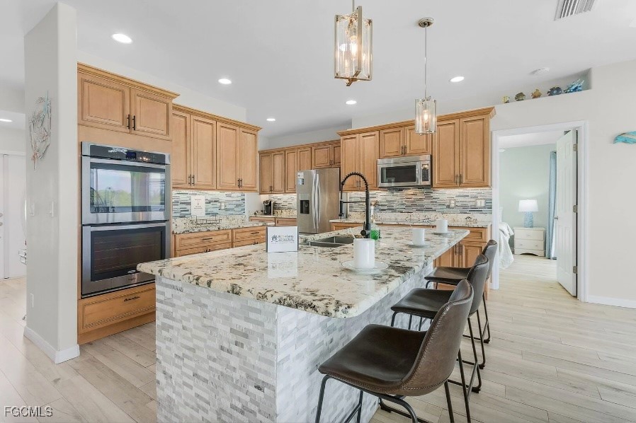 4885 East Riverside Drive Fort Myers, FL 33905 - Photo 9 of 45 a kitchen with stainless steel appliances granite countertop a stove top oven a refrigerator a sink and a dining table with wooden floor