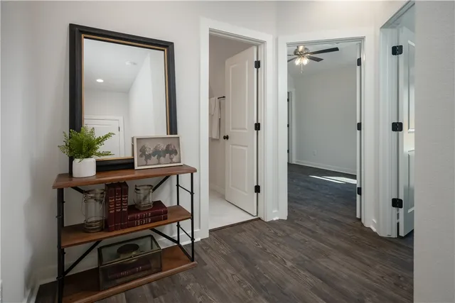 a view of a hallway with wooden floor and a bathroom