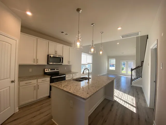 a kitchen with granite countertop a sink a counter top space stainless steel appliances and cabinets